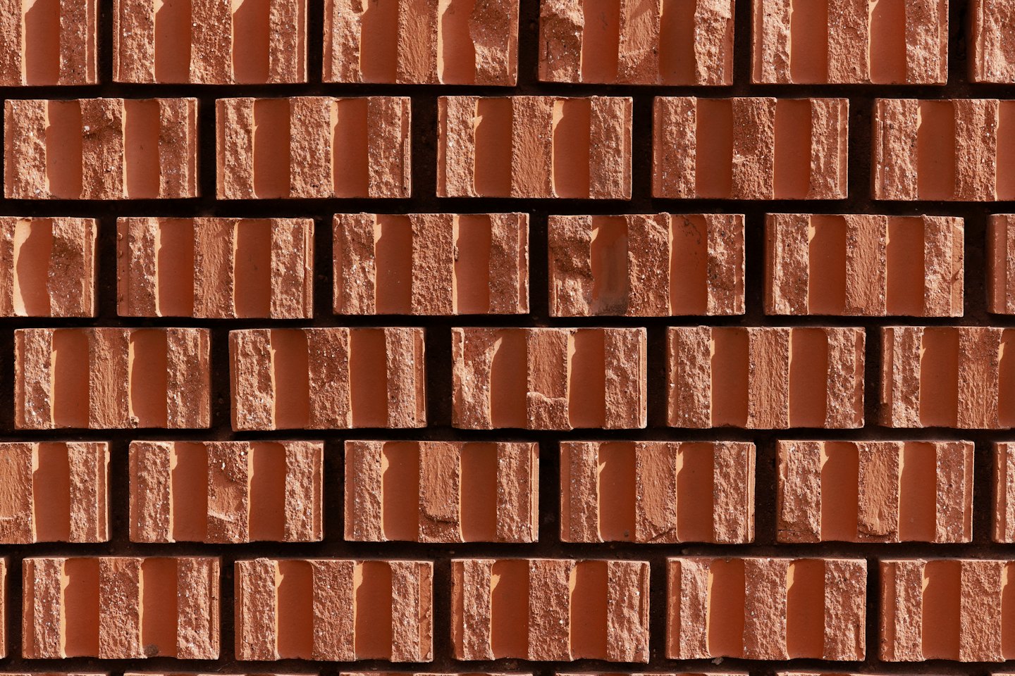 Textured reddish-brown bricks laid in staggered rows on a wall.