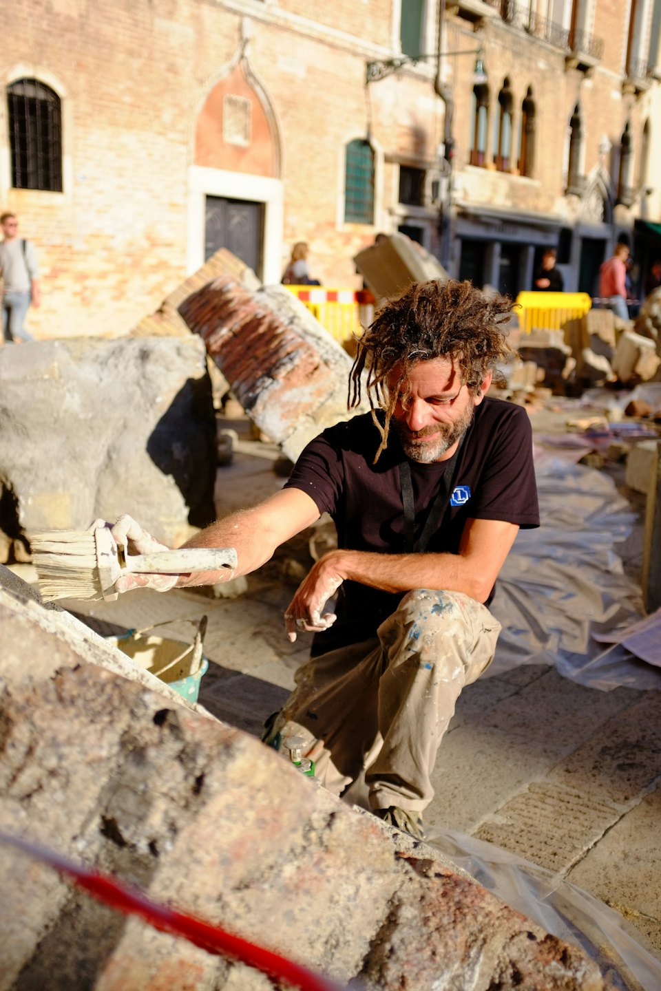 A man brushes dust off a large stone architectural fragment.